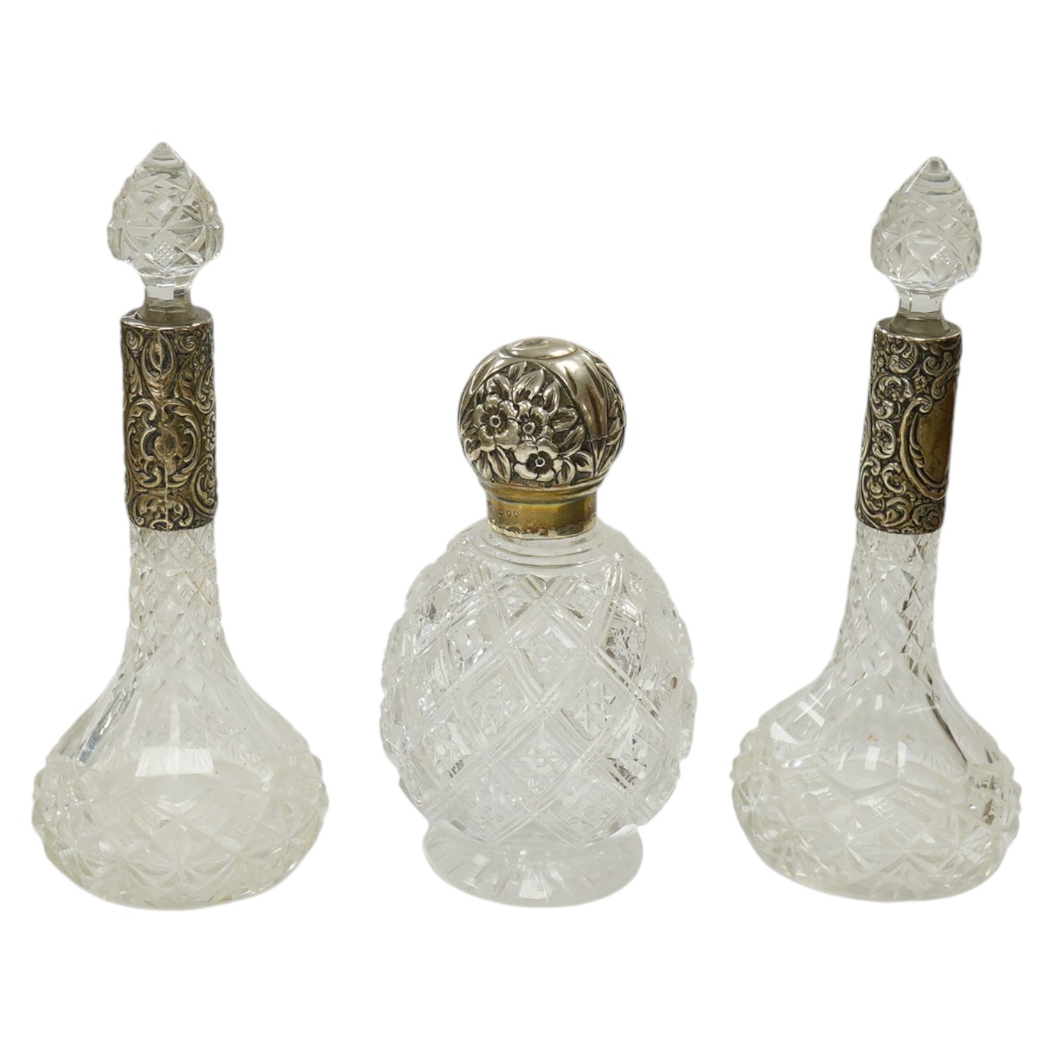 A Victorian silver lidded cut glass scent bottle, 15cm and a pair of silver collared scent bottles and stoppers, 20cm high. Condition - fair